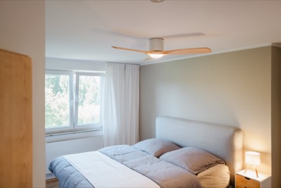 Schlafzimmer mit Bett, Nachttischen und Fenster zum Grün